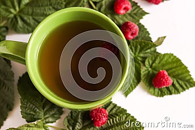 Summer raspberry tea in green cup. Herbal tea served with fresh raspberry leaves Stock Photo