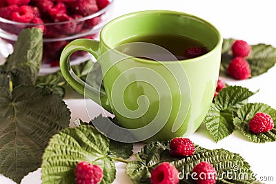 Summer raspberry tea in green cup. Herbal tea served with fresh raspberry leaves Stock Photo