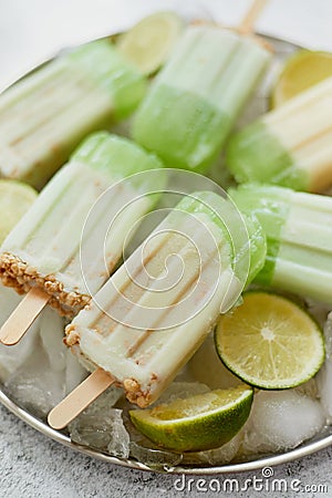 Summer refreshing homemade lime popsicles with chipped ice over stone background Stock Photo