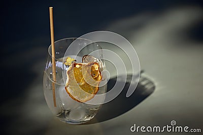 Summer refreshment aperitif cocktail in glass with ice rocks, bamboo straw and eatable flowers on a table Stock Photo