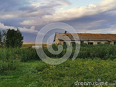 Rural landscape with cloudy sky at sunset and abandoned house Stock Photo