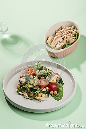 Summer salad of chicken and fresh vegetables: cucumber, cherry tomato, corn and spinach on a green background with reflections and Stock Photo