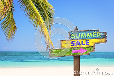 Summer sale written on pastel colored wooden direction signs, beach and palm tree background Stock Photo