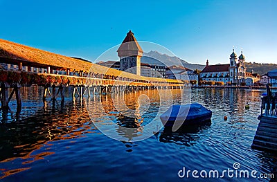 Summer scenery of Chapel Bridge Kapellbrucke over Reuss River in Lucerne Old Town, Switzerland, with a boat parking on the riv Stock Photo