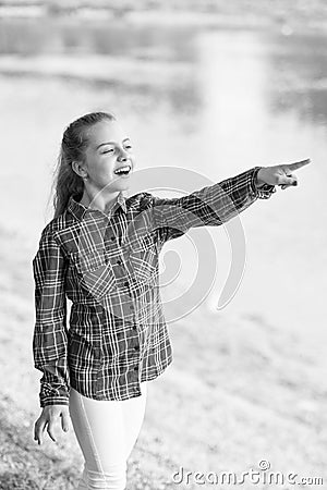 Always summer. Small girl pointing finger at river on summer landscape. Adorable child with long blond hair in casual Stock Photo