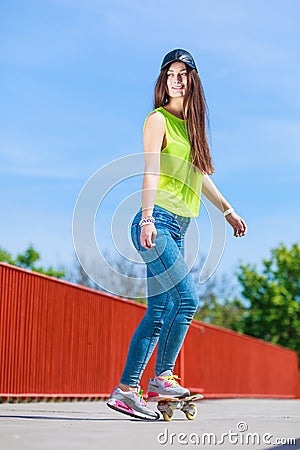 Teen girl skater riding skateboard on street. Stock Photo