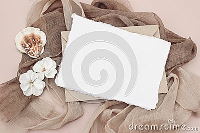 Summer stationery still life scene. Blank greeting card mock-up and craft envelope. Beige silk scarves, white flowers Stock Photo