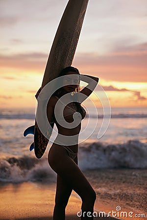 Summer. Surfer girl silhouette with surf board on sunset beach Stock Photo