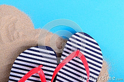 Striped slippers on sand and blue background Stock Photo