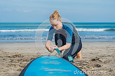 Summer time and active rest concept. Young surfer woman beginner fastens leash across leg, going to surf on big barral Stock Photo