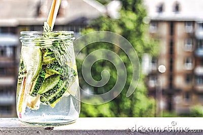 Detox drink from cucumber, lemon and mint on the background of a modern city. Summer time Stock Photo