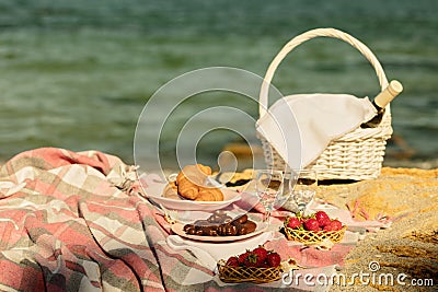 Summer time at the sea. Romantic picnic on the beach - wine, strawberries and sweets. Stock Photo