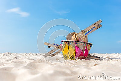 Summer Travel. Bikini and Flip-flops ,hat, fish star and bag near beach chair on sandy beach against blue sea and sky background, Stock Photo