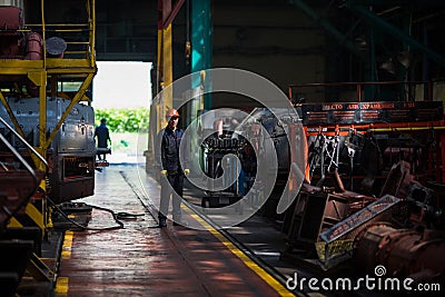 Workers stand behind the machines at the factory and work. Editorial Stock Photo