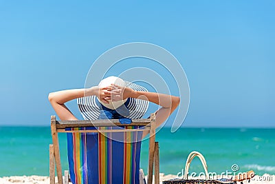 Summer Vacation. Beautiful young asian woman relaxing and happy on beach chair with cocktail coconut juice in holiday summer, blue Stock Photo