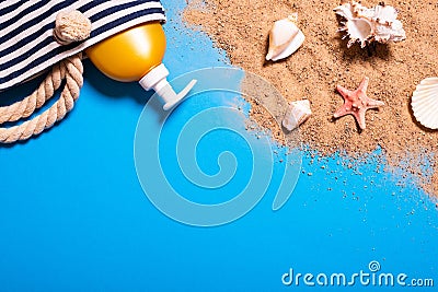 Summer vacation concept with seashells, starfish, women`s beach bag and suntan lotion bottle on a blue background and sand Stock Photo