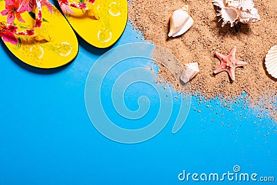 Summer vacation concept with seashells, starfish and women`s beach sandals on a blue background and sand. Stock Photo