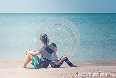 Summer Vacation and Holiday Concept : Happy family day trip at the sea, Woman and child sitting back to back relax on sand beach. Stock Photo