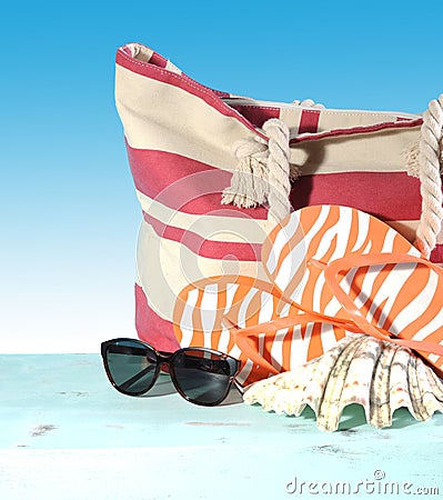Summer vacation holiday gear with red and white strip beach bag, flip flop things, shell and sunglasses Stock Photo