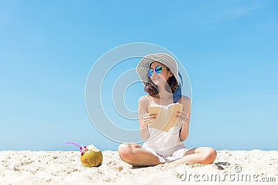 Summer Vacation. Smelling asian women relaxing and reading book on the beach, so happy and luxury in holiday summer, blue sky back Stock Photo