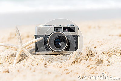 Summer Vacations. Vintage old camera of tourism on sandy beach with star fish. Stock Photo