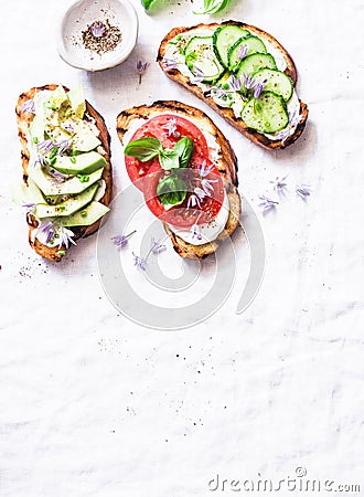 Summer variations of sandwiches - with cream cheese, avocado, tomato and cucumber on a light background, top view. Healthy diet fo Stock Photo