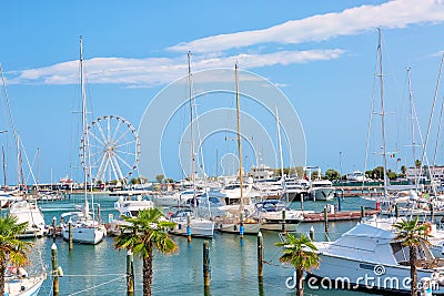 Summer view of pier with ships, yachts and other boats with ferris wheel in Rimini, Italy Stock Photo