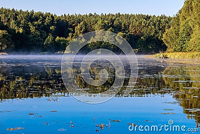 Summer water scenery. Fishing on a forest lake in the early morning. Fog over the water, forest, water surface Stock Photo