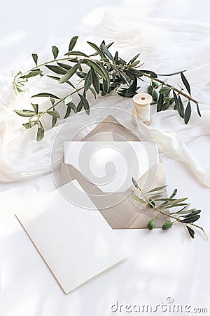 Summer wedding stationery mock-up scene. Blank greeting cards, envelope, olive branches and silk ribbon. White Stock Photo