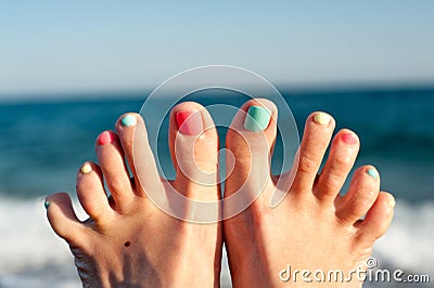 Summertime enjoyment! Feet on the beach. Blue ocean waves backgr Stock Photo