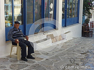 Greek old man sitting in a village of Naxos in Greece. Editorial Stock Photo