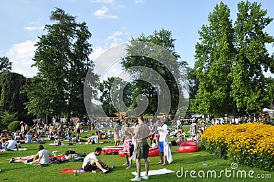 Summertime: people in ZÃ¼rich Seefeld lake promenade and park are taking a sun bath or a swim Editorial Stock Photo