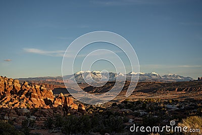 Sun Begins To Set Over The Fiery Furnace With The Snowy La Sal Mountains In The Distance Stock Photo