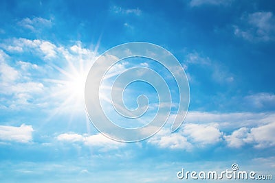 The sun with bright rays in the blue sky with white light clouds Stock Photo