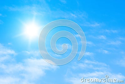 The sun with bright rays in the blue sky with white light clouds Stock Photo