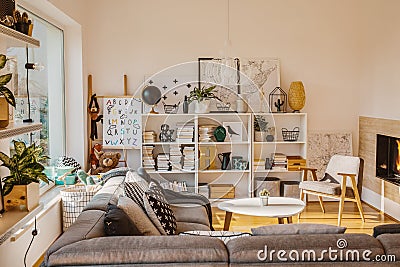 Sun coming through a large window into a cozy, scandinavian living room interior with a bio fireplace, books, decorations and toys Stock Photo