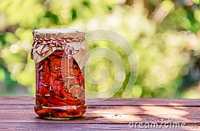 Sun dried tomatoes in glass jar on wooden table. Delicious gift. Vegetarian food. Stock Photo