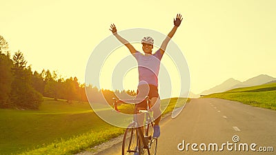 SUN FLARE: Pro cyclist cheerfully rides road bike with no hands after victory. Stock Photo