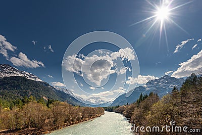 Sun over rural river between mountains Stock Photo