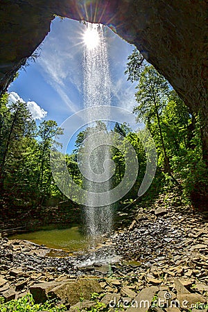 Sun Piercing Through A Tall Waterfall Stock Photo