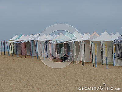 Sun protection tents on the sand of the bathing beach in the town of Nazaré, person resting i Editorial Stock Photo