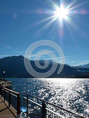 View over the glittering lake to the mountain with a radiant sun Stock Photo