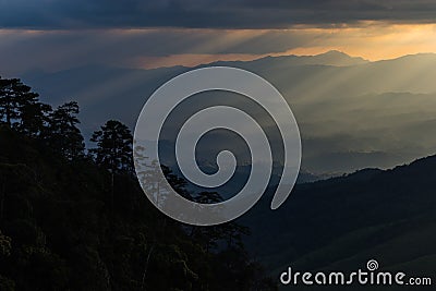 Sun rays breaking through the clouds over a mountain landscape Stock Photo