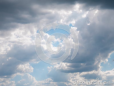 Sun rays breaking through a large cloud formed in the sky surrounded by diffuse clouds Stock Photo