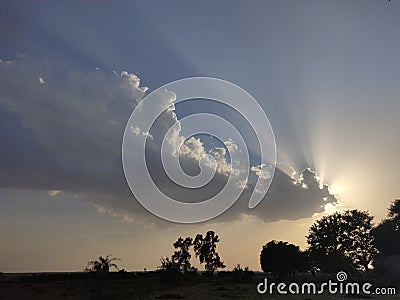 Sun rays spreading behind cloud at sunset Stock Photo