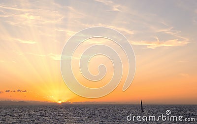 Sun rays at sunset with sailboat on the coast of Donostia, Cantabrico Sea. Stock Photo