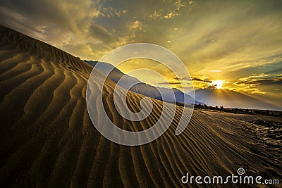 Sun rise at sand dunes against the background of distant colorful mountain range and sunrise sky, Ladakh, Himalaya, Jammu & Stock Photo