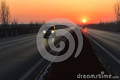 The sun rises at the end of the stretch of the road Stock Photo
