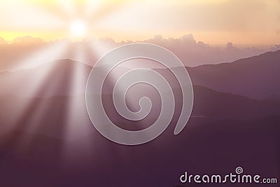 Sun rising behind mountains in summer. Sun rays causing lensflare over the hills in a scenic environment. Forest slopes Stock Photo