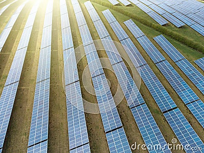 Sun rising over array solar panel farm in rows over sunny field. Renewable green electricity energy generation bright sunshine Stock Photo